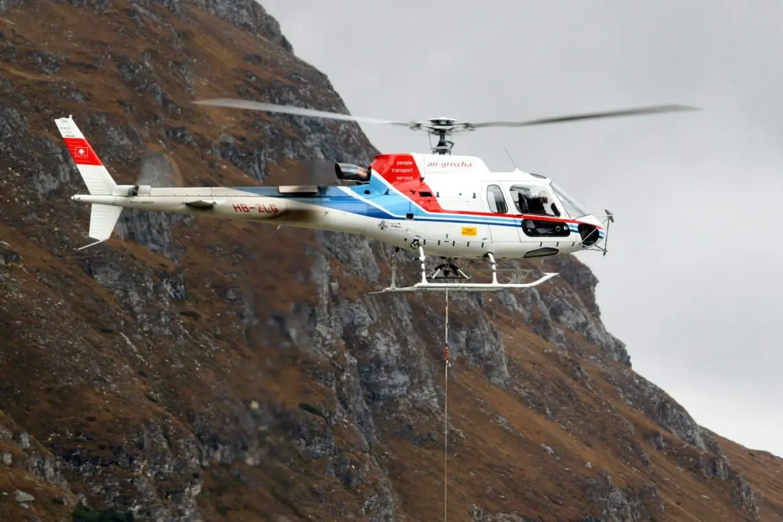 Hélicoptère de secours en vol avec son treuil au-dessus d un versant de montagne
