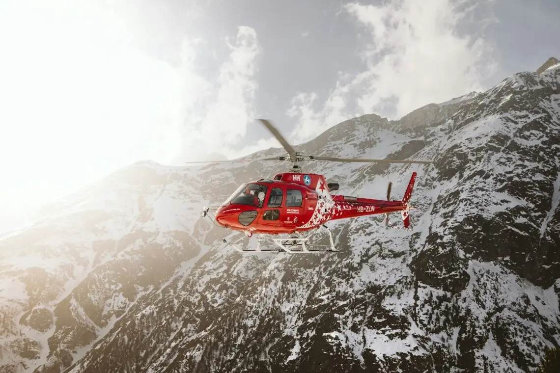 Hélicoptère de secours en montagne survolant un massif enneigé