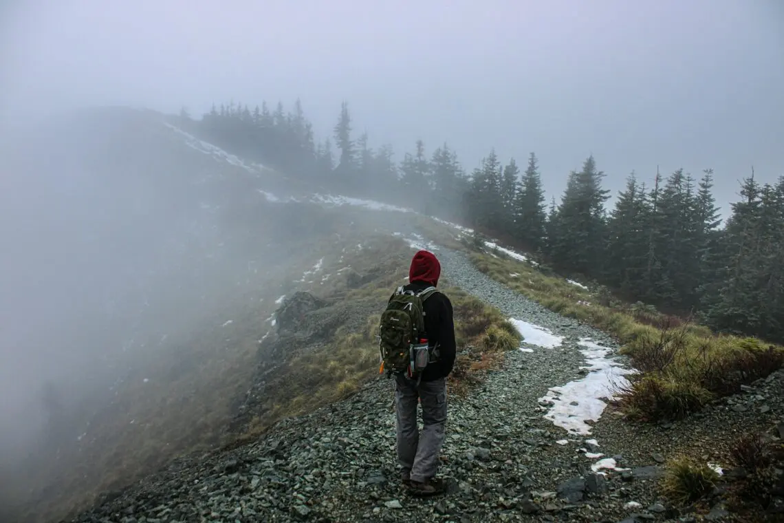 Randonneur en veste de pluie sur un sentier dans le brouillard