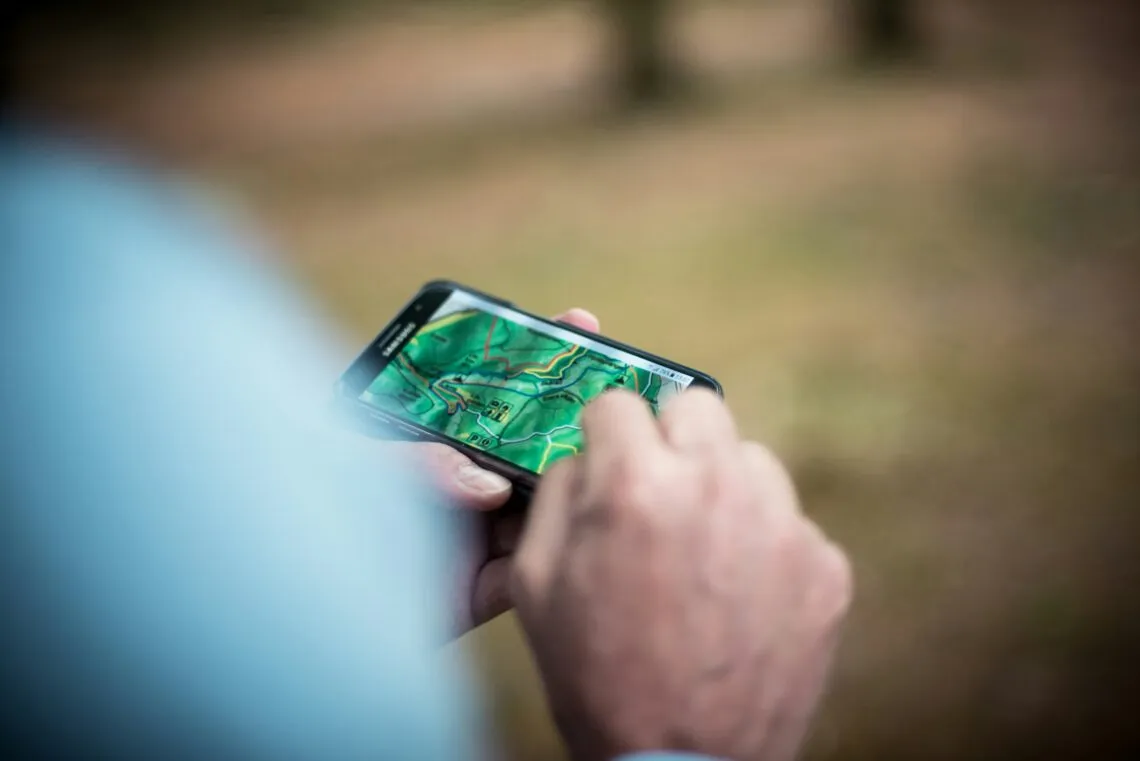 Randonneur consultant une carte topographique sur son smartphone en pleine nature