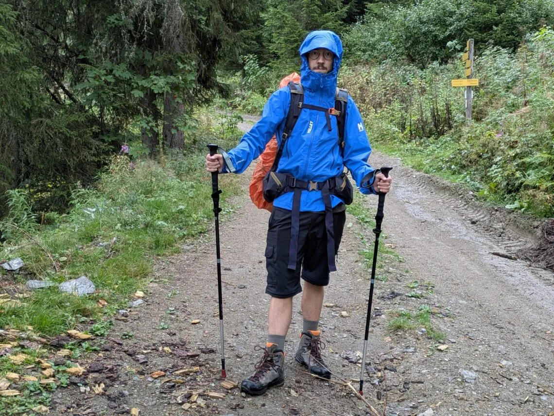 Randonneur en veste imperméable Millet, capuche relevée, sous la pluie sur le Tour du Beaufortain