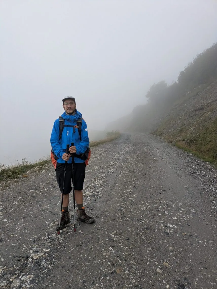 Randonneur en veste imperméable Millet sur une piste noyée dans le brouillard, Tour du Beaufortain